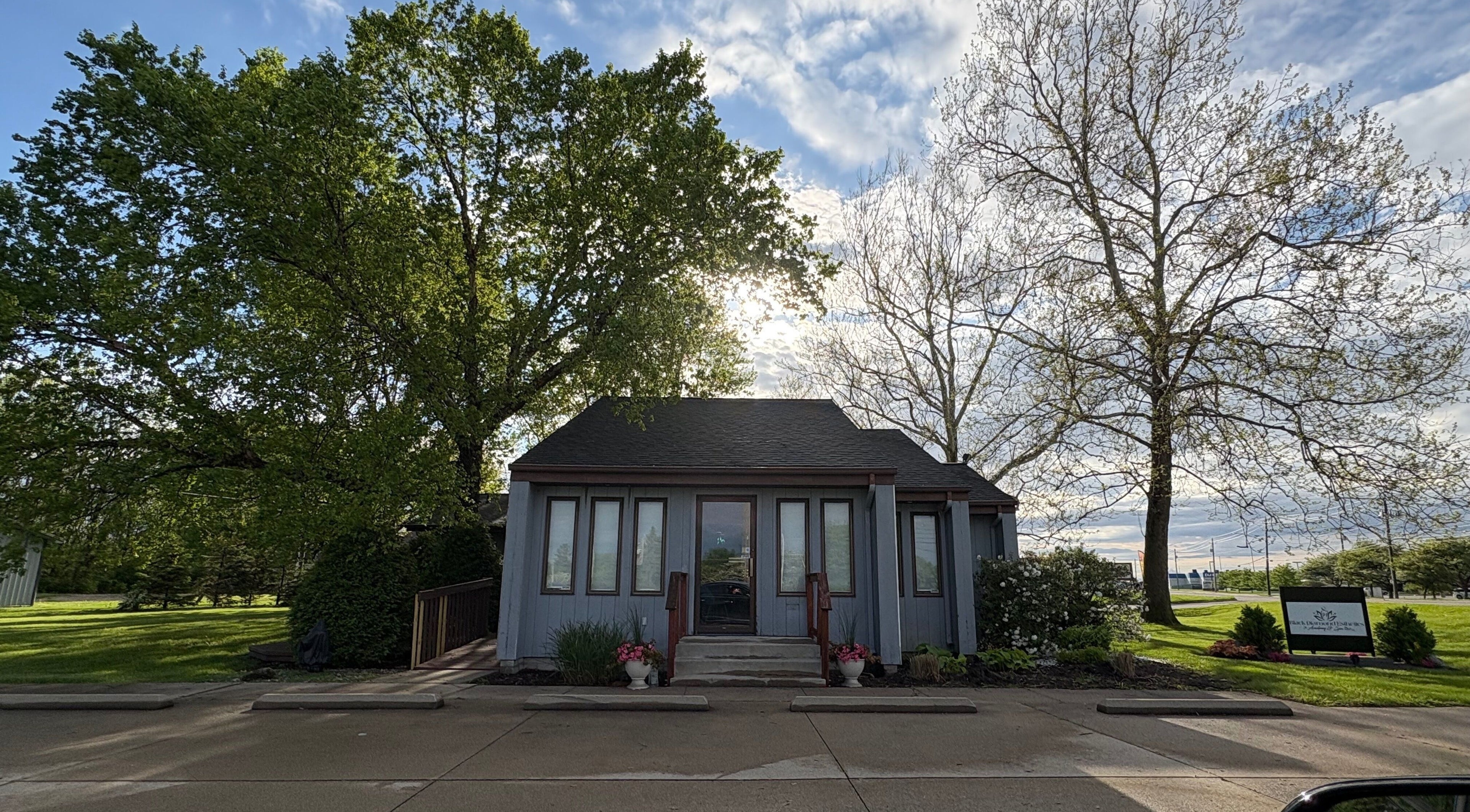 Charming facade of Enchanted Beauty Haven in Muncie, Indiana, US with lush greenery and a bright sky.