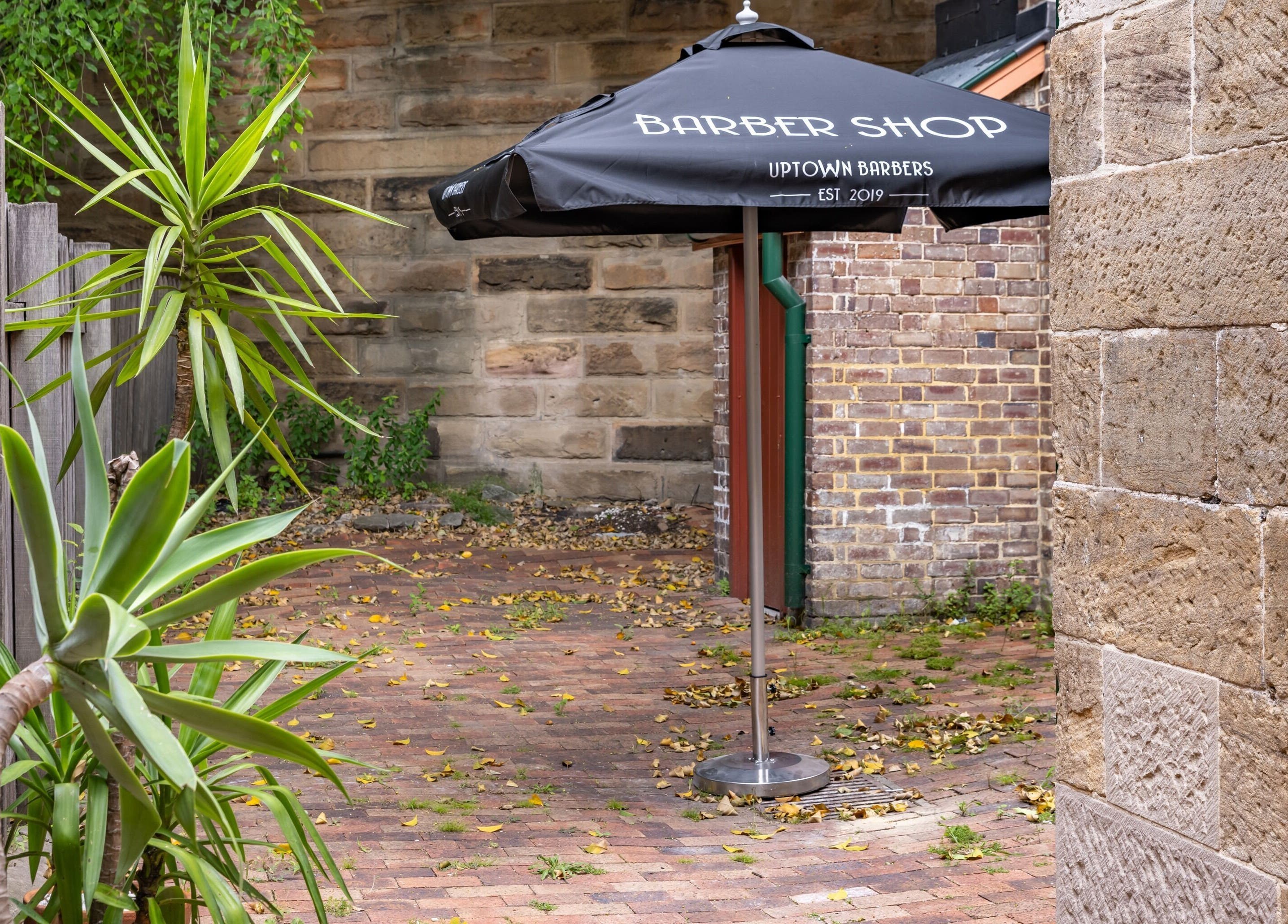 Charming patio with a barber shop umbrella at Uptown Barbers The Rocks, The Rocks, New South Wales, AU.