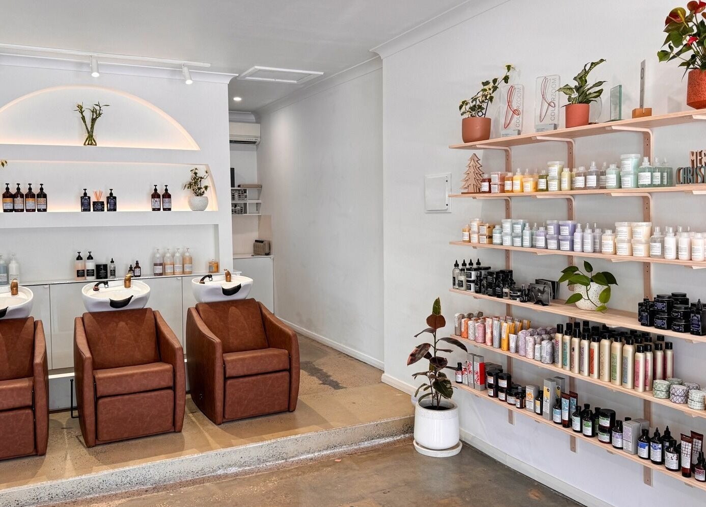 Elegant interior of Mooi Studio in Glenelg, South Australia, AU featuring salon chairs and product shelves.
