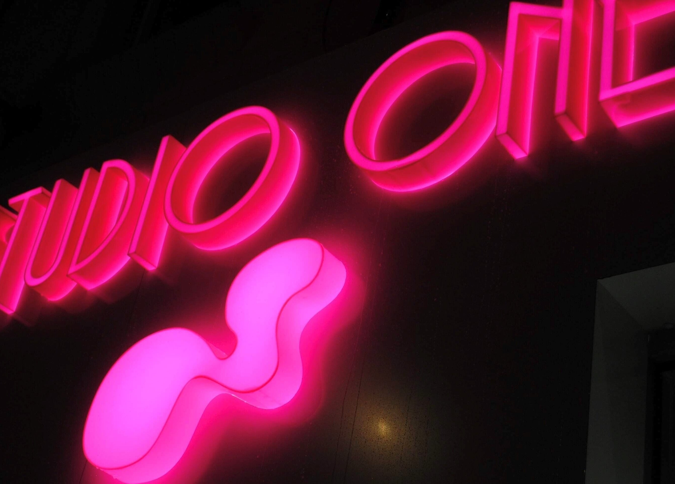 Glowing neon sign of Studio One Nails and Beauty, New Milton, England, GB, illuminating the night.