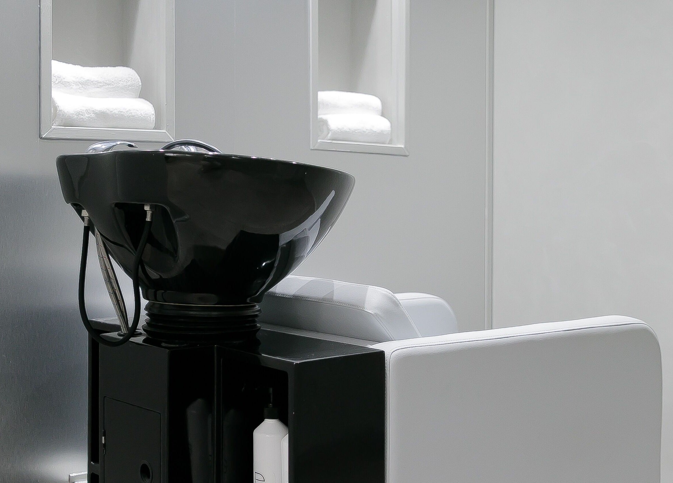 Moderne wasruimte bij Essence Barbers (Oudenoord), Utrecht, Utrecht, NL met een zwart wasbak en witte handdoeken.