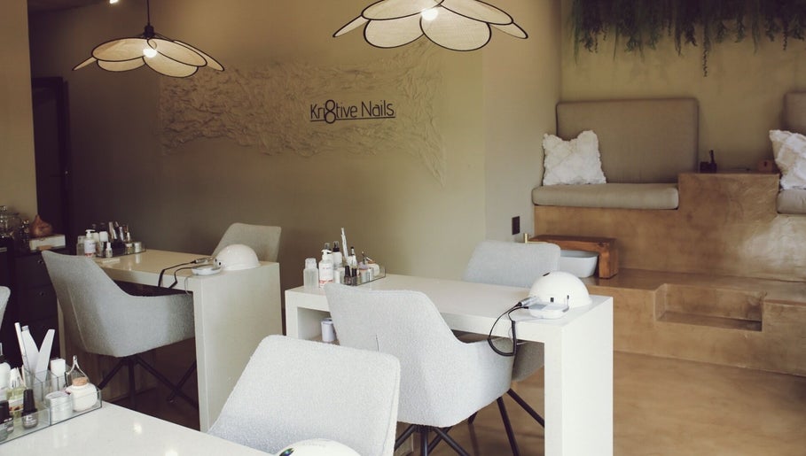 Elegant interior of Kri8tive Nails salon in Pretoria, Gauteng, ZA with manicure stations and cozy seating.