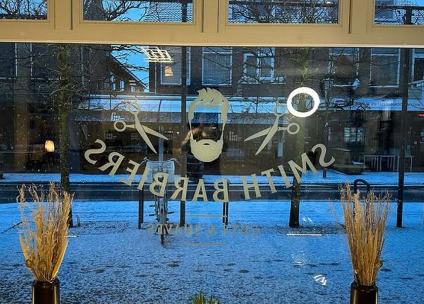 Uitzicht op besneeuwd straat vanaf Smith Barbiers in Woudenberg, Utrecht, NL met logo op raam.