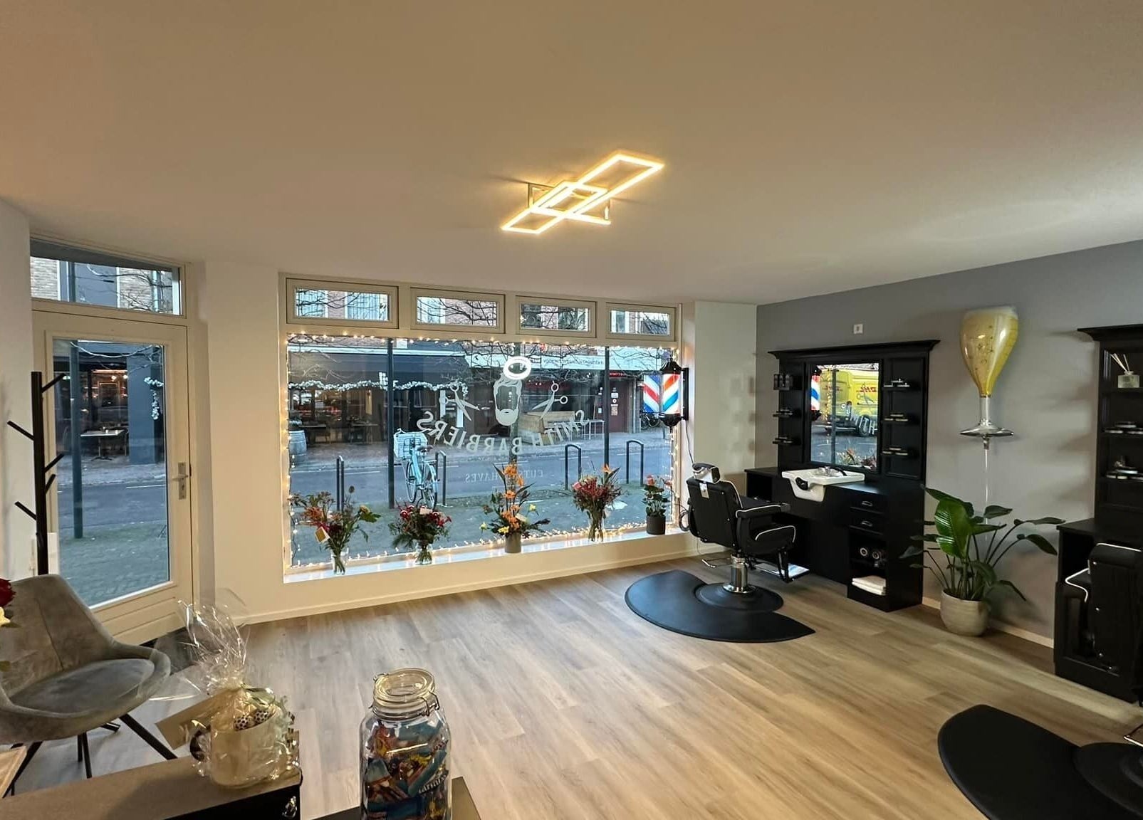 Smith Barbiers interieur met moderne inrichting in Woudenberg, Utrecht, NL. Stijlvolle kapsalon met bloemen en verlichting.