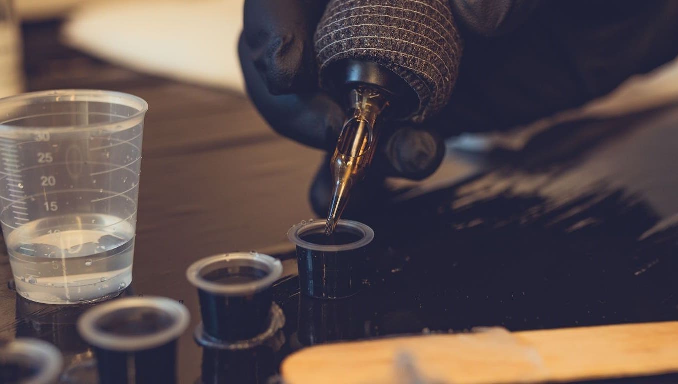 Tattoo artist prepares ink at Epic Tattoos Guildford, Guildford, England, GB with precision and care.