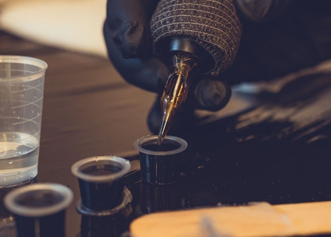 Tattoo artist prepares ink at Epic Tattoos Guildford, Guildford, England, GB with precision and care.