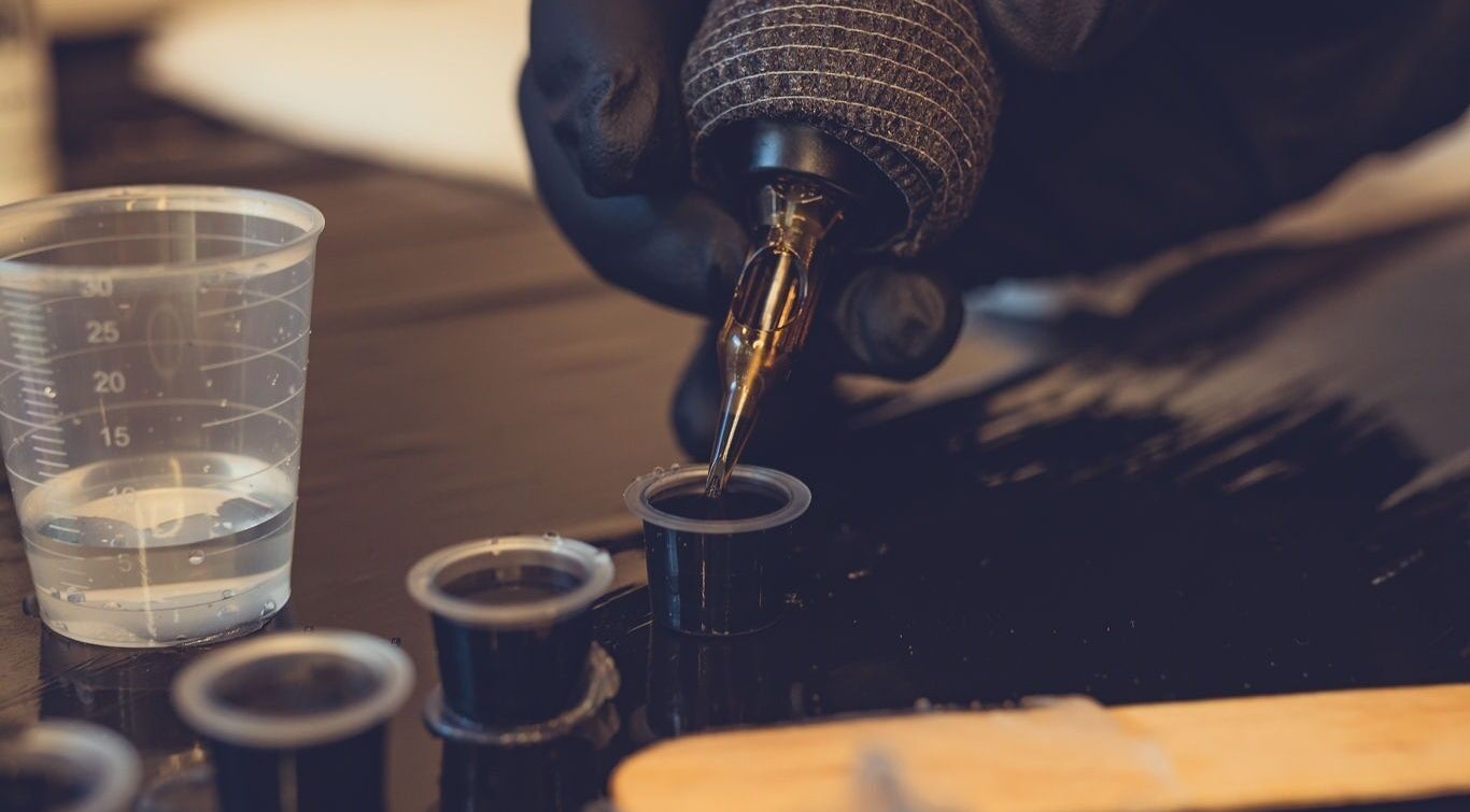 Tattoo artist prepares ink at Epic Tattoos Guildford, Guildford, England, GB with precision and care.