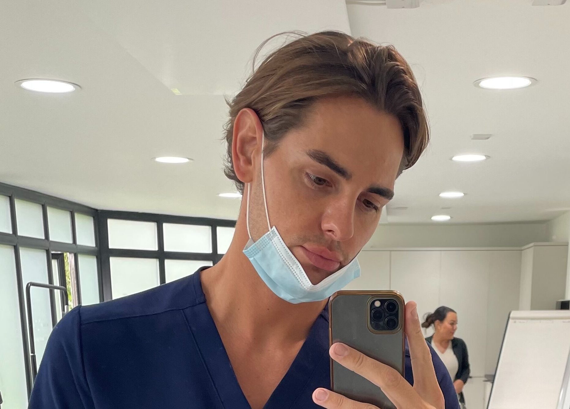 Inside Jack Anthony Aesthetics in London, England, a person in a blue uniform captures a selfie.