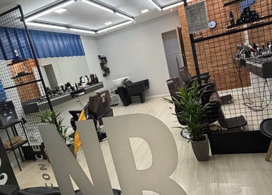 Interior elegante da Nonato Barbearia em Minas Gerais, BR, com cadeiras de cabeleireiro e espelhos iluminados.