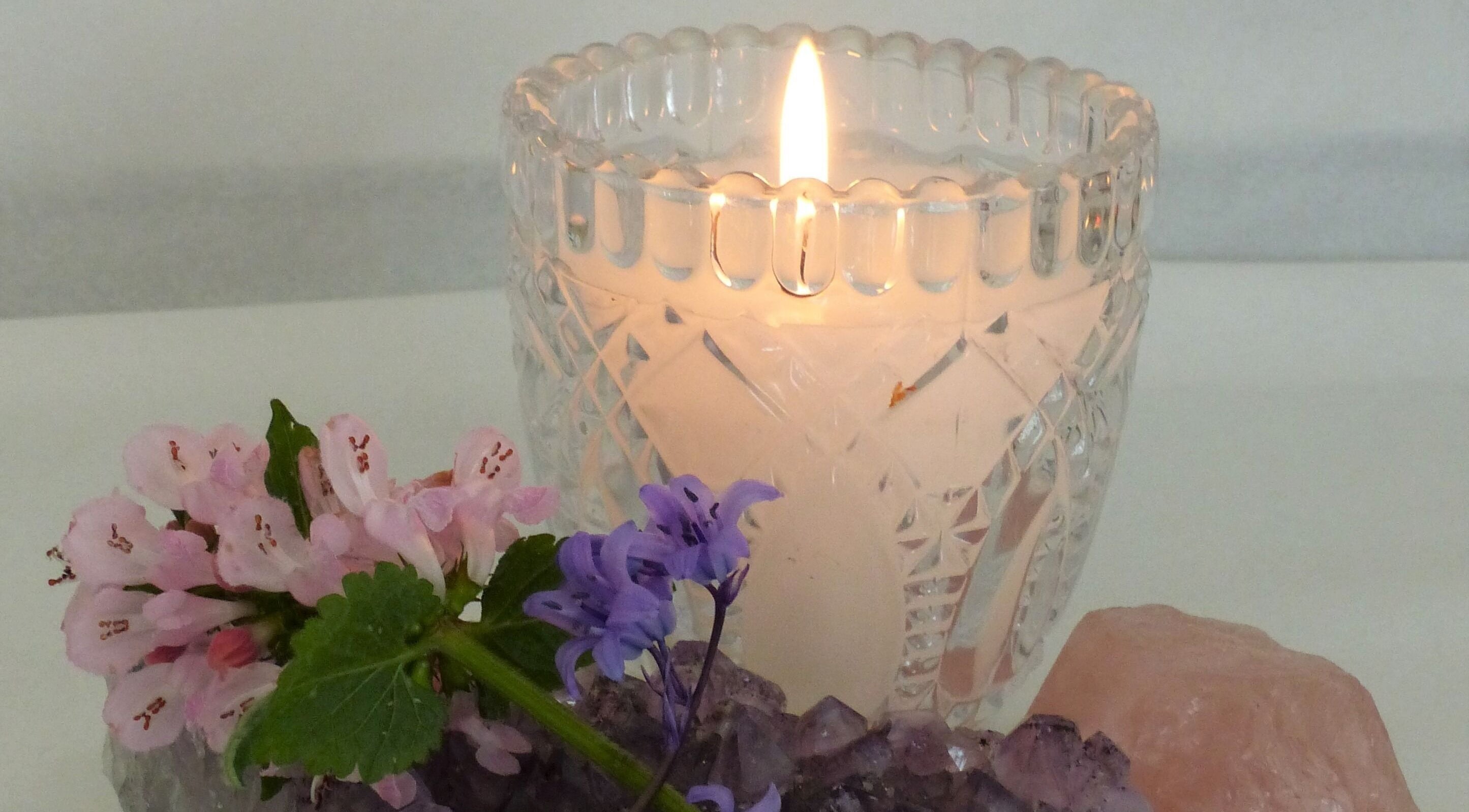 A lit candle beside fresh flowers at Sycamore Beauty, Northampton, England, GB.