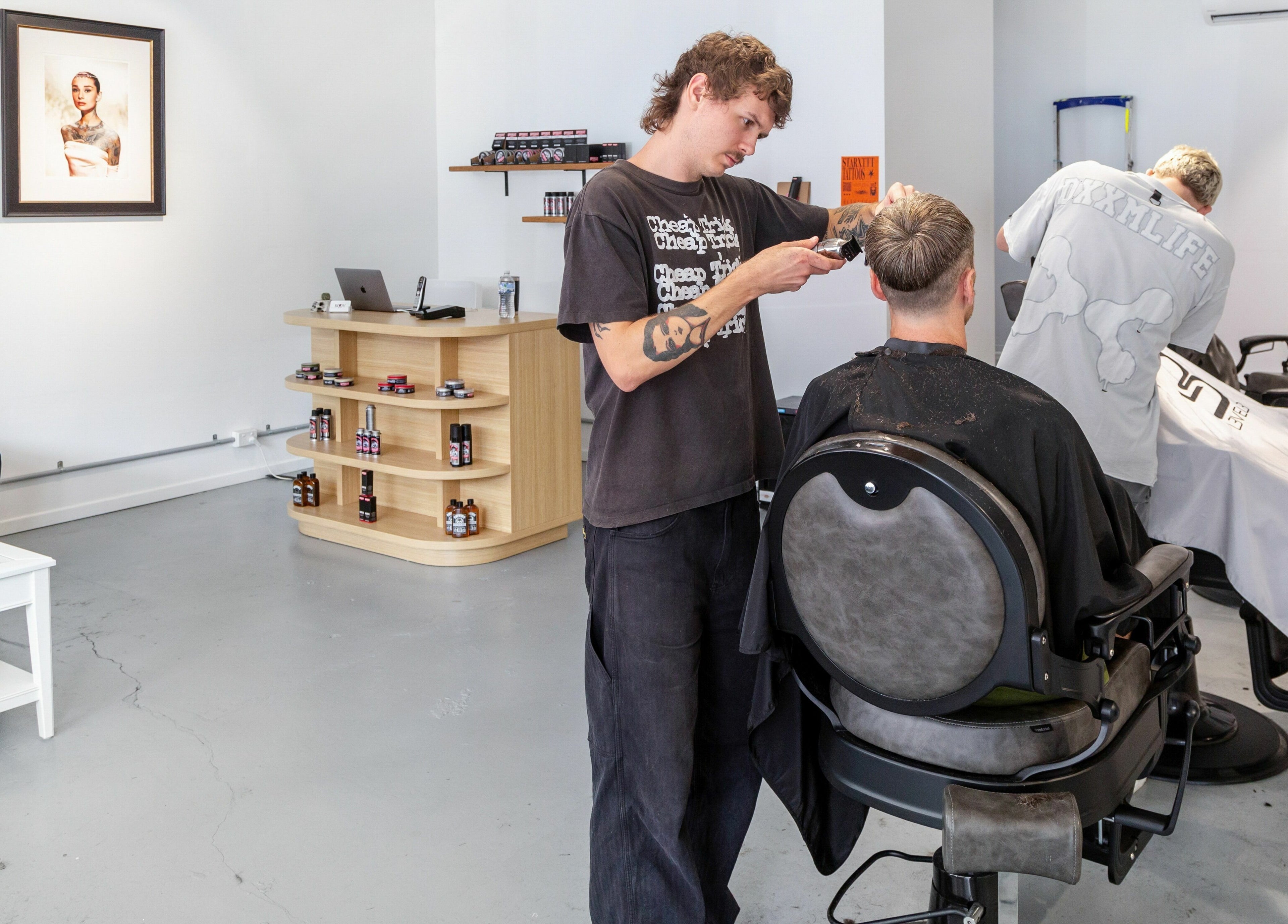 Barber skillfully cuts hair at Boy Barbershop - Coolangatta, QLD, AU. Modern, welcoming interior.