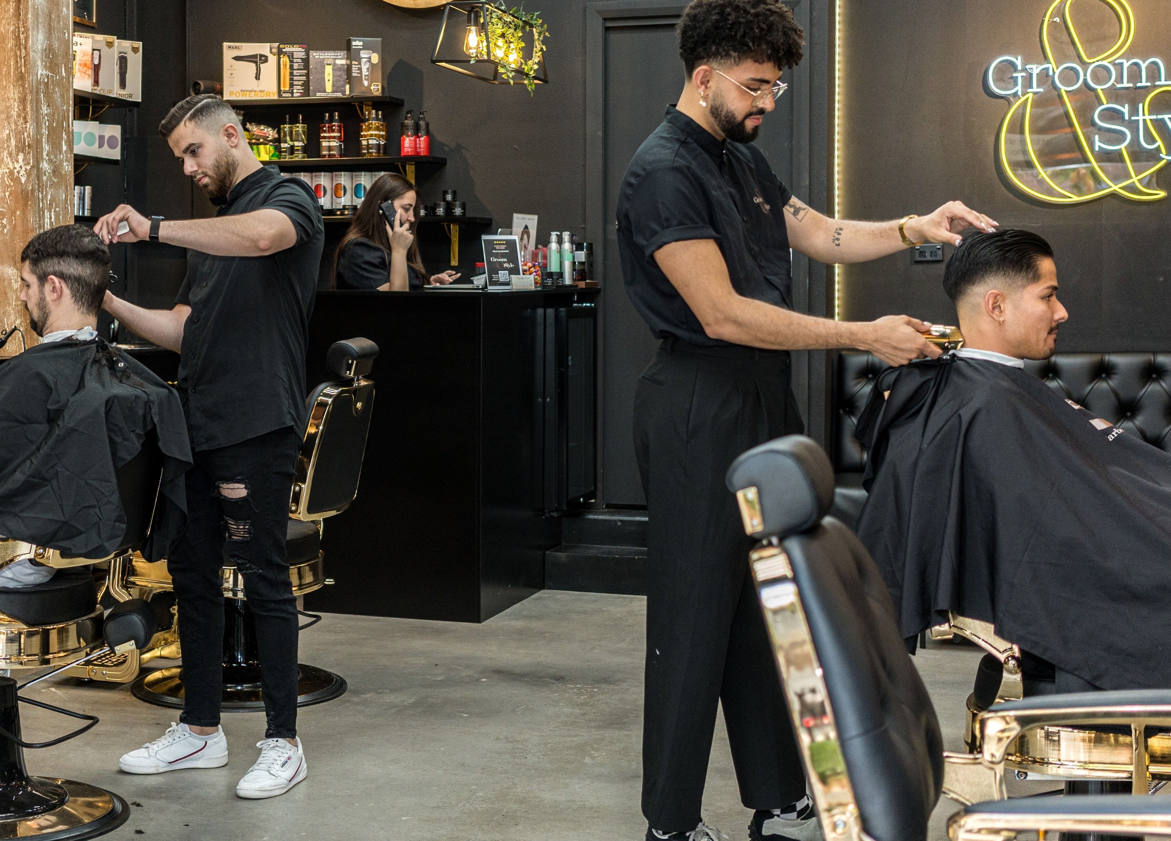 Two stylists at Groom & Style Barber Shop, Waterloo, New South Wales, AU, expertly cutting clients' hair.