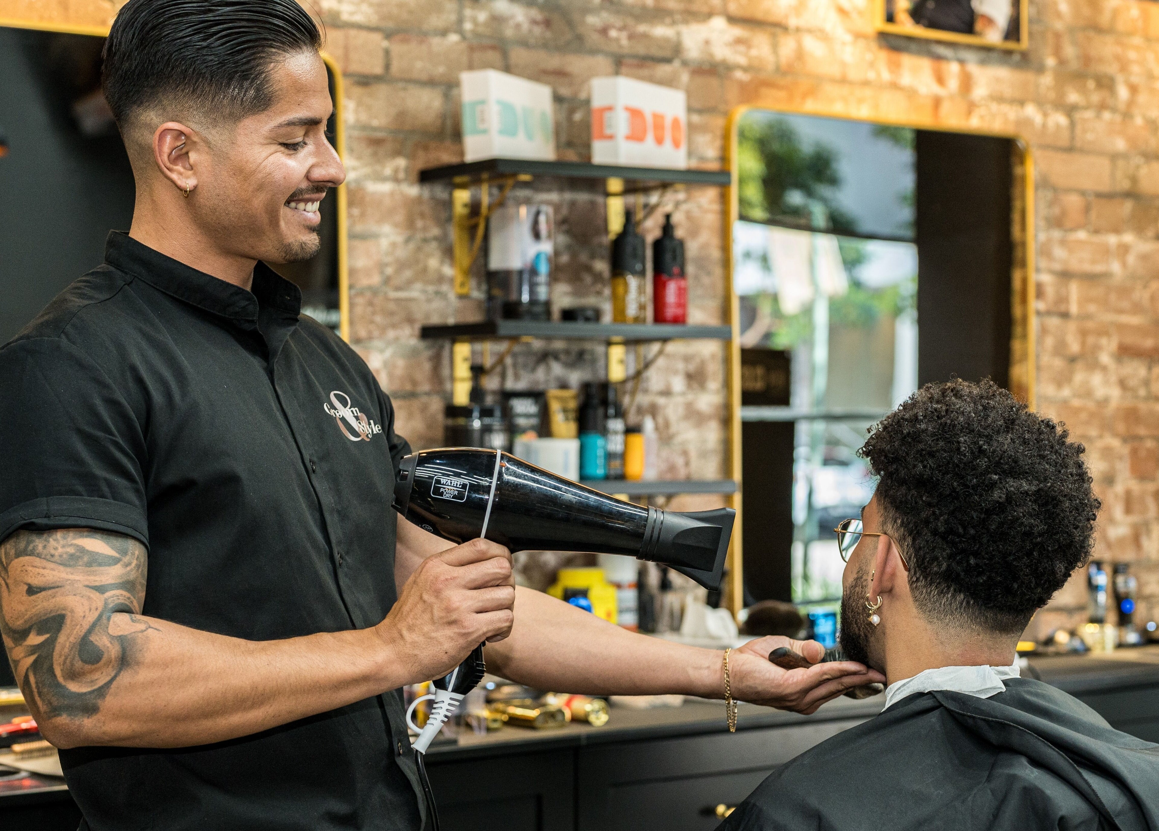 Stylist at Groom & Style Barber Shop in Waterloo, NSW, AU, expertly blow-drying client's hair.