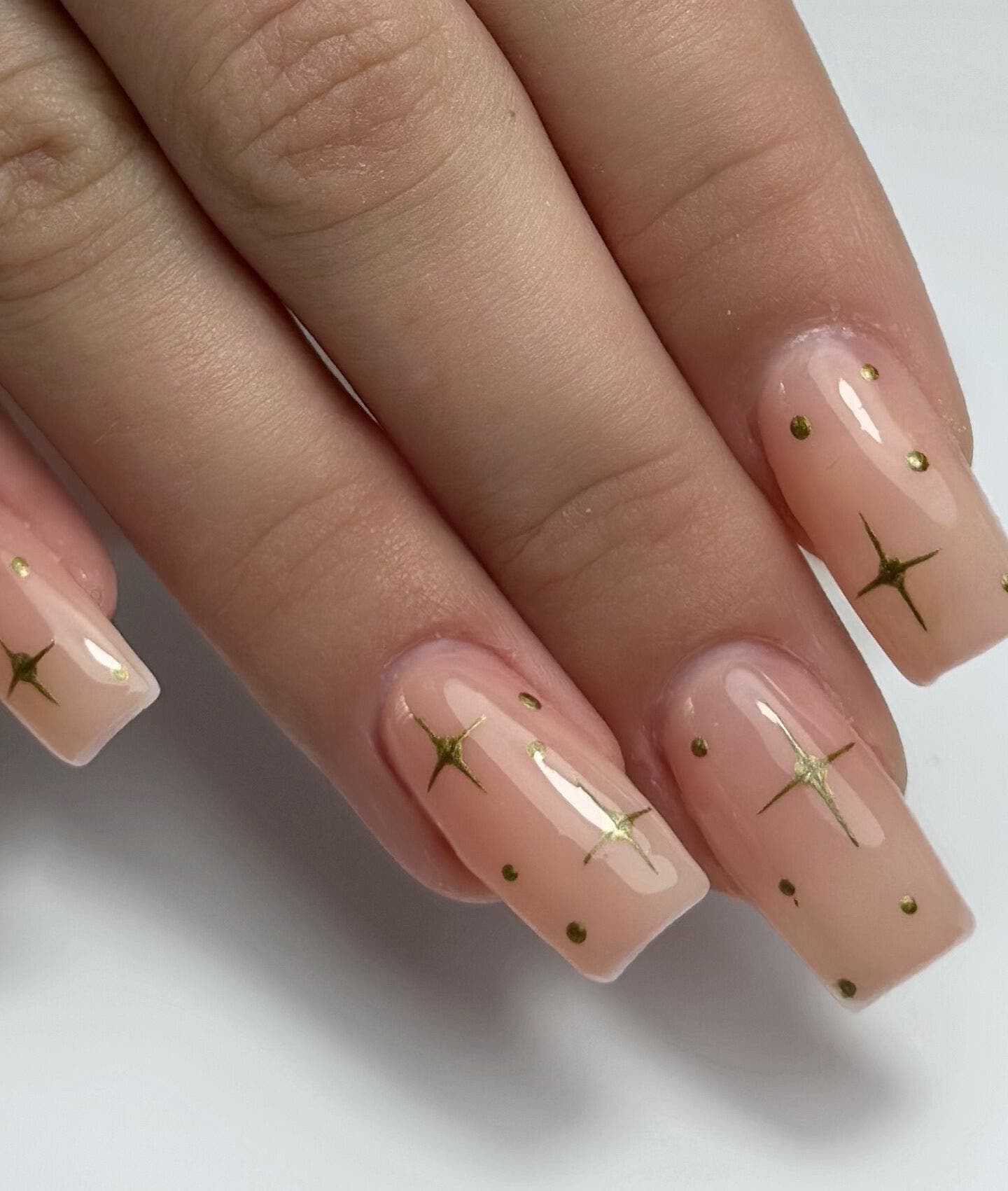 Elegant nail art with gold stars at Shaped & Polished, Mosta, MT. Perfect manicure showcasing glossy finish.