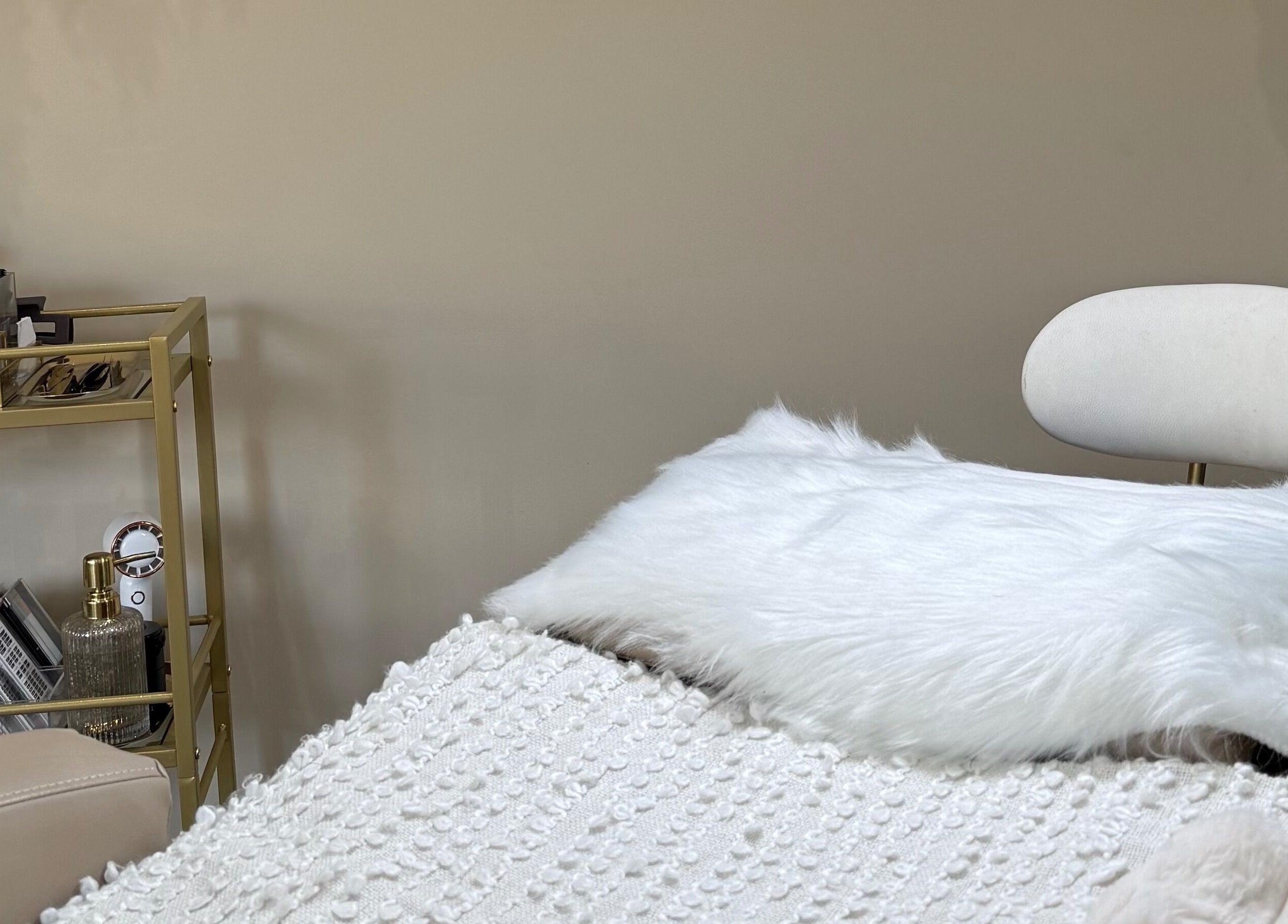 Cozy treatment room at Beauty Box By Zoe in Billingshurst, England, GB with a plush chair and gold shelving.