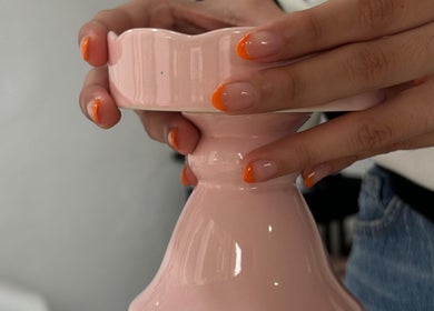 Manicura naranja en Mimo Beauty Center, Mérida, Yucatán, MX sobre pedestal rosa.