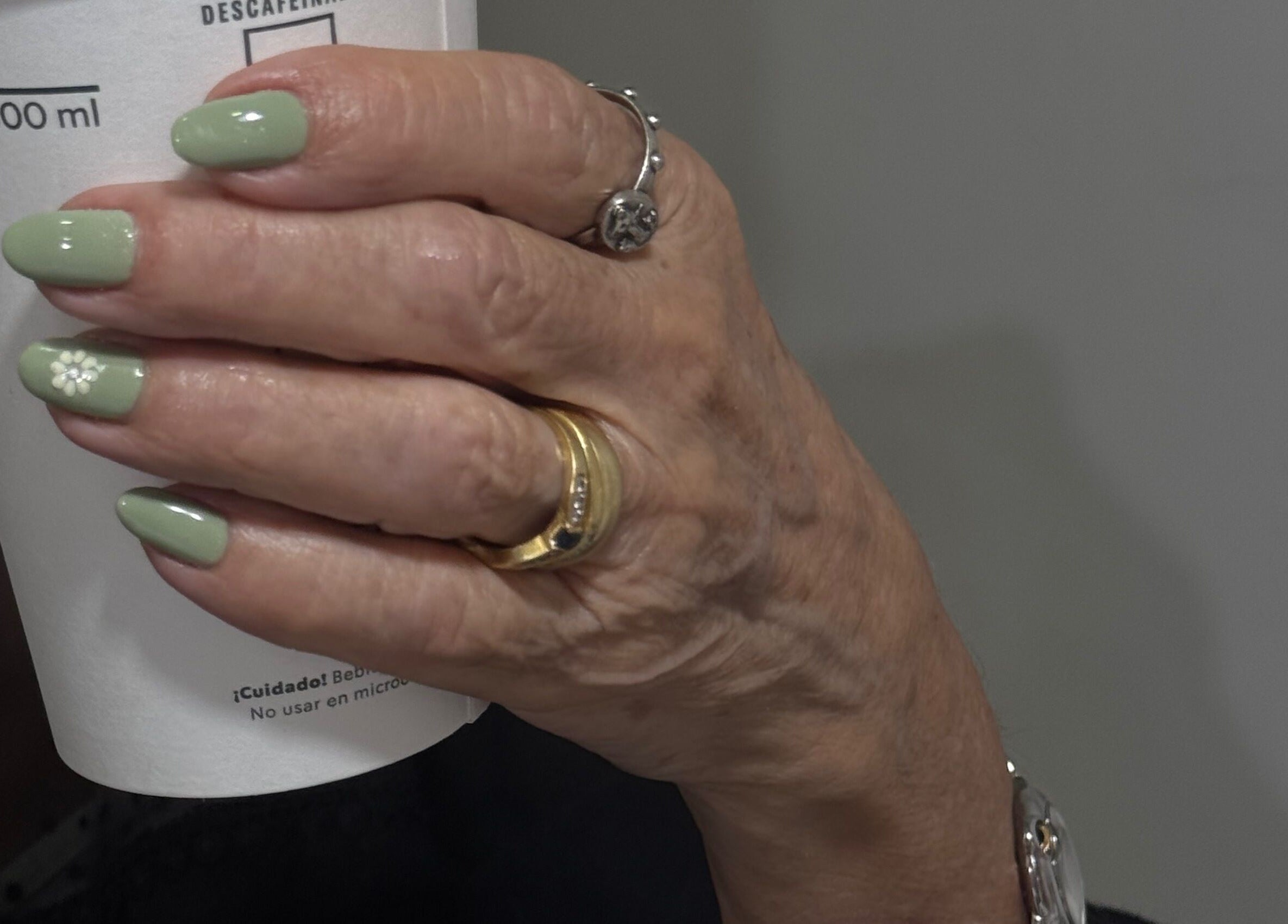 Una mano con uñas verdes lleva un café en Mimo Beauty Center, Mérida, Yucatán, MX.