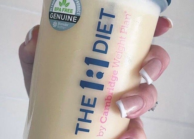 Hand holding 1:1 Cambridge Diet Plan shake, available at Waltham On The Wolds, England, GB.