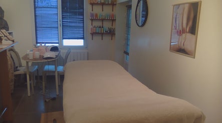Salle de soin à La Douce'heure Esthétique, Nouzilly, Centre-val De Loire, FR avec table et produits cosmétiques.