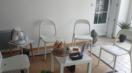 Espace d'attente à La Douce'heure Esthétique, Nouzilly, Centre-val De Loire, FR, avec chaises blanches et déco zen.