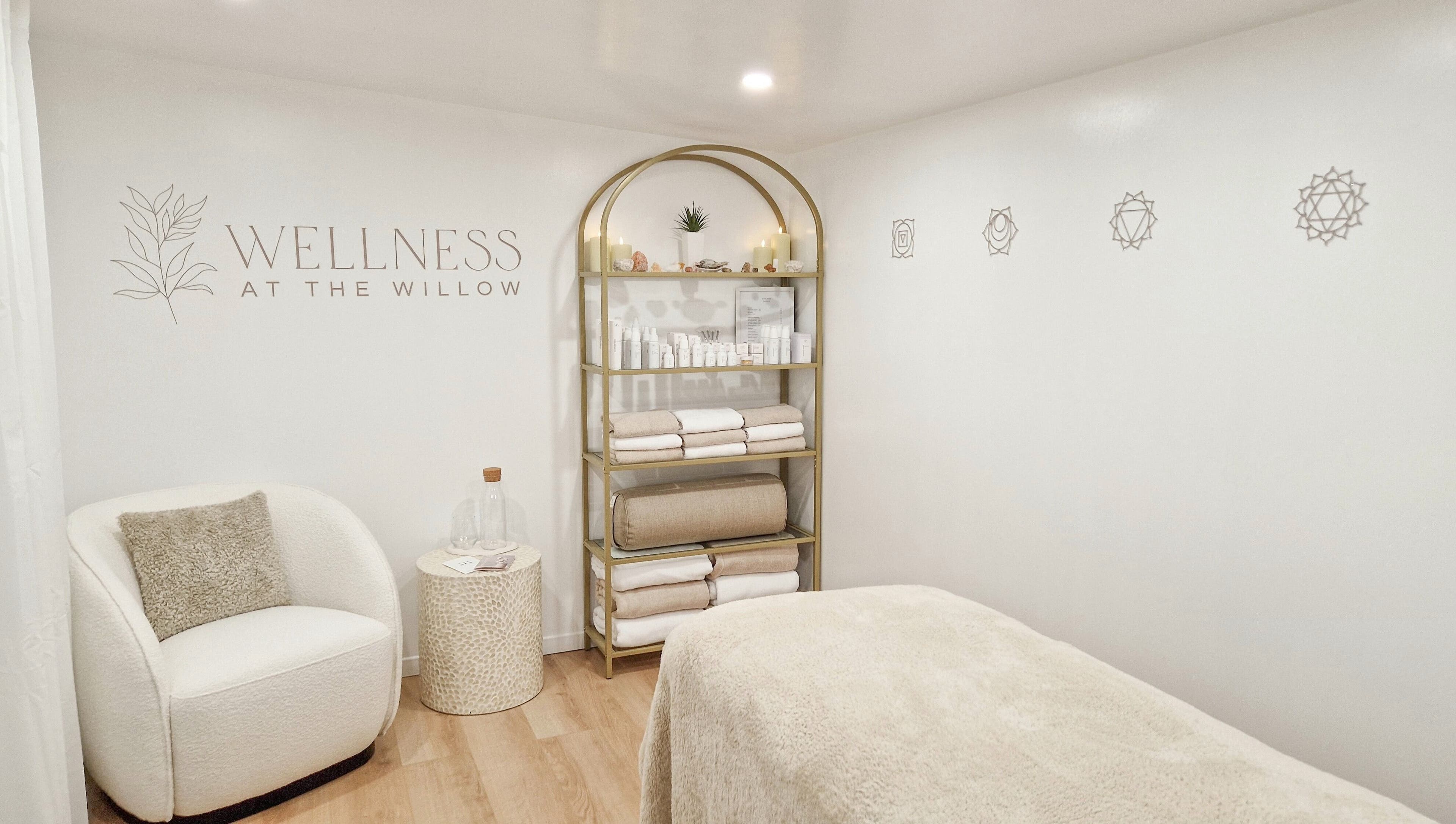 Tranquil treatment room at Wellness at The Willow, Leyland, England, GB with cozy chair and shelves of products.
