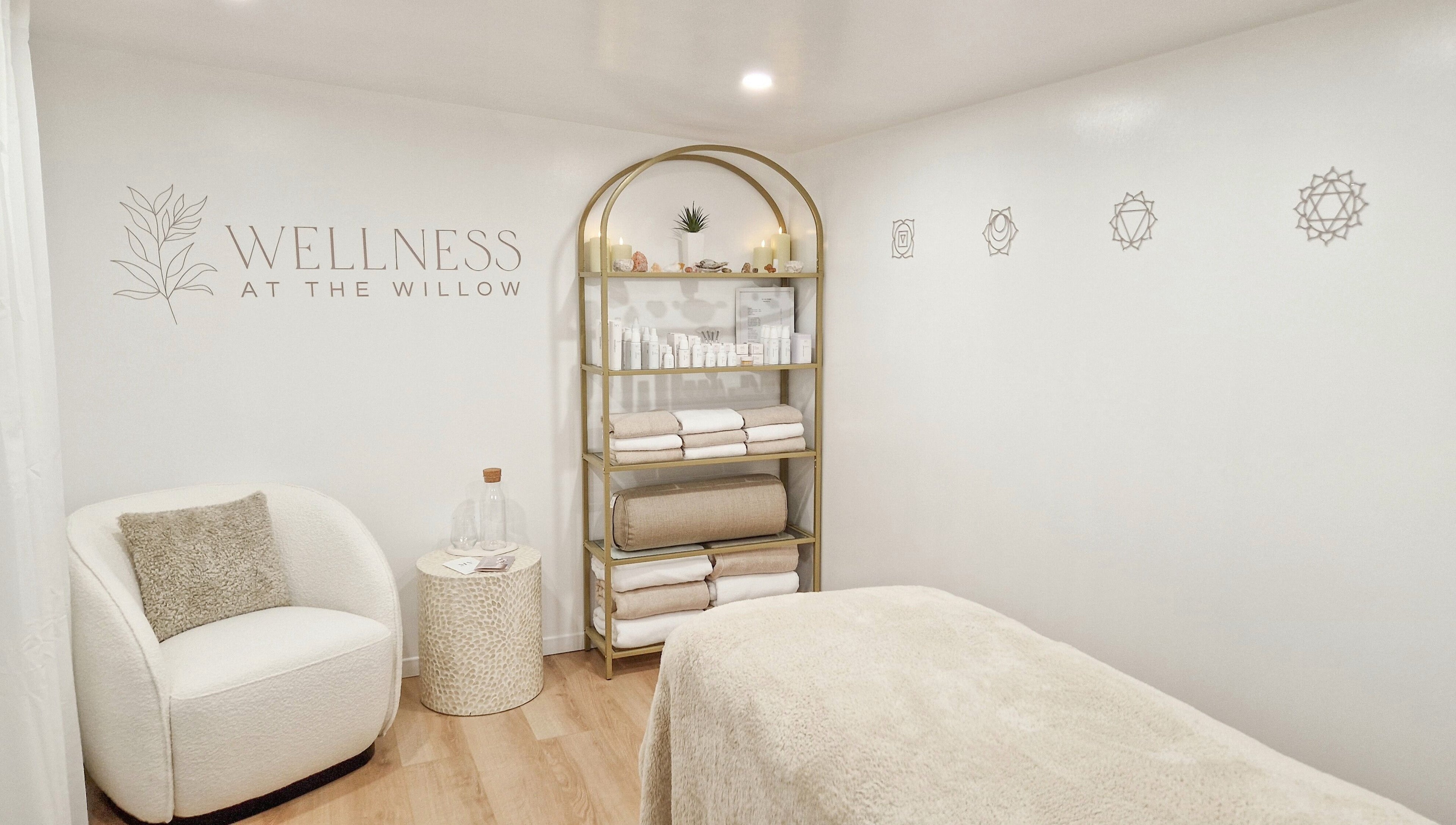 Tranquil treatment room at Wellness at The Willow, Leyland, England, GB with cozy chair and shelves of products.