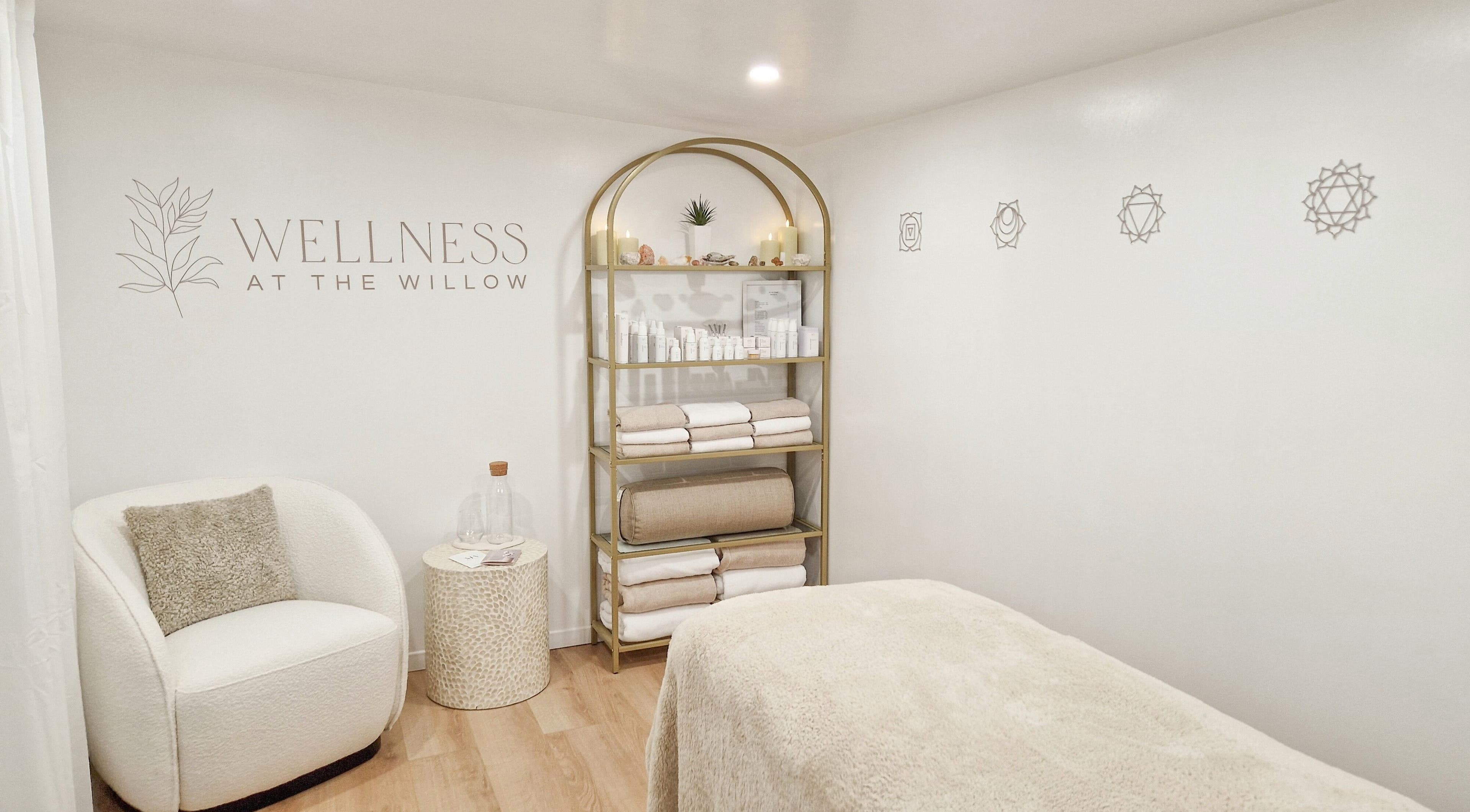 Tranquil treatment room at Wellness at The Willow, Leyland, England, GB with cozy chair and shelves of products.