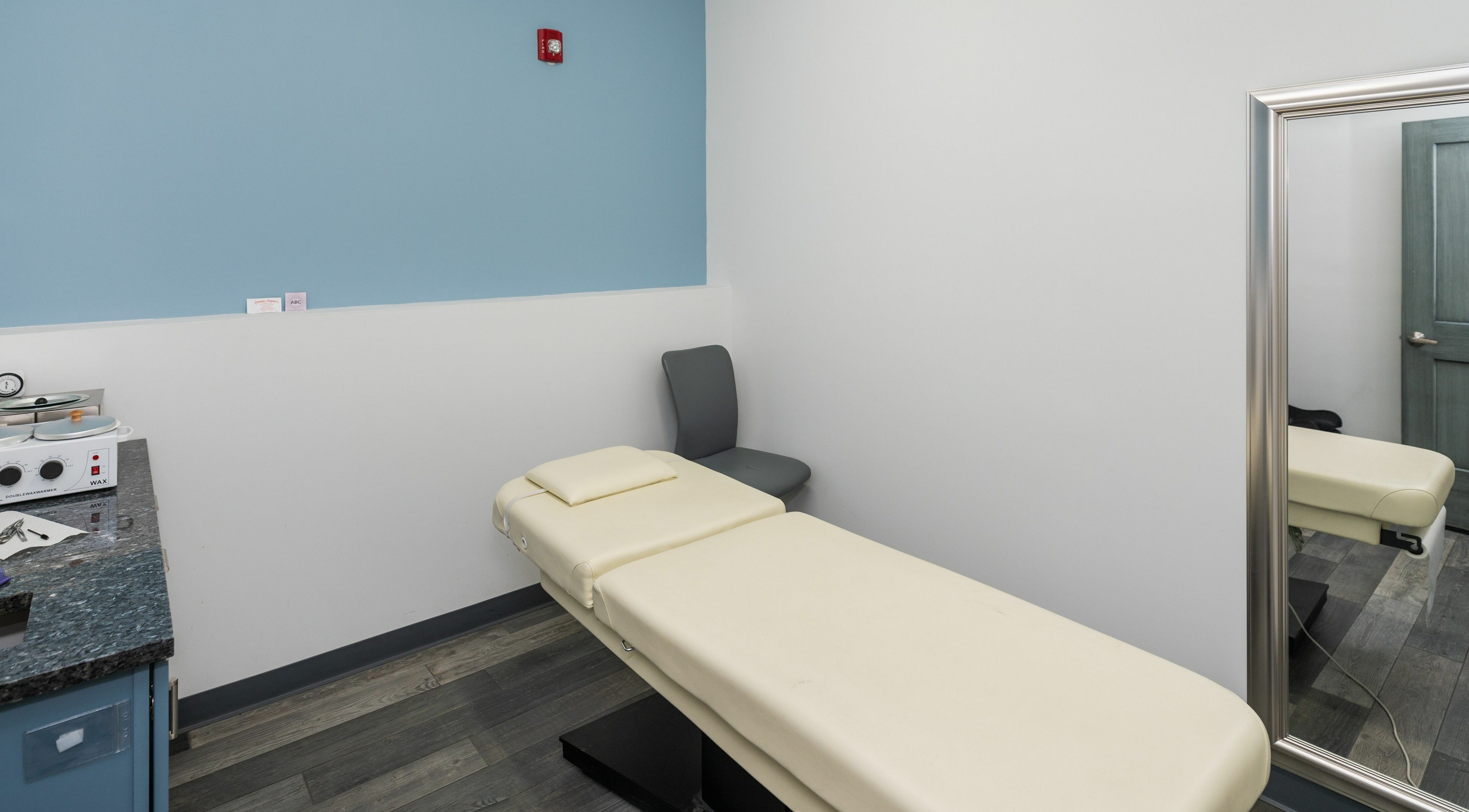 Tranquil therapy room at Cara Mia Nails in Lakewood, Colorado. Features a massage table, mirror, and calming decor.