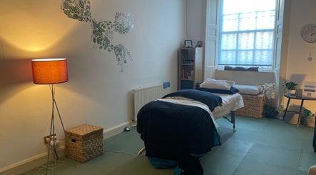 Cozy massage room at Calmer Being, Edinburgh, Scotland, GB with warm lighting and soothing decor.