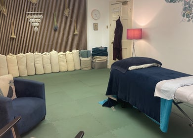 Tranquil therapy room at Calmer Being, Edinburgh, Scotland, GB, featuring a massage table and cozy seating.