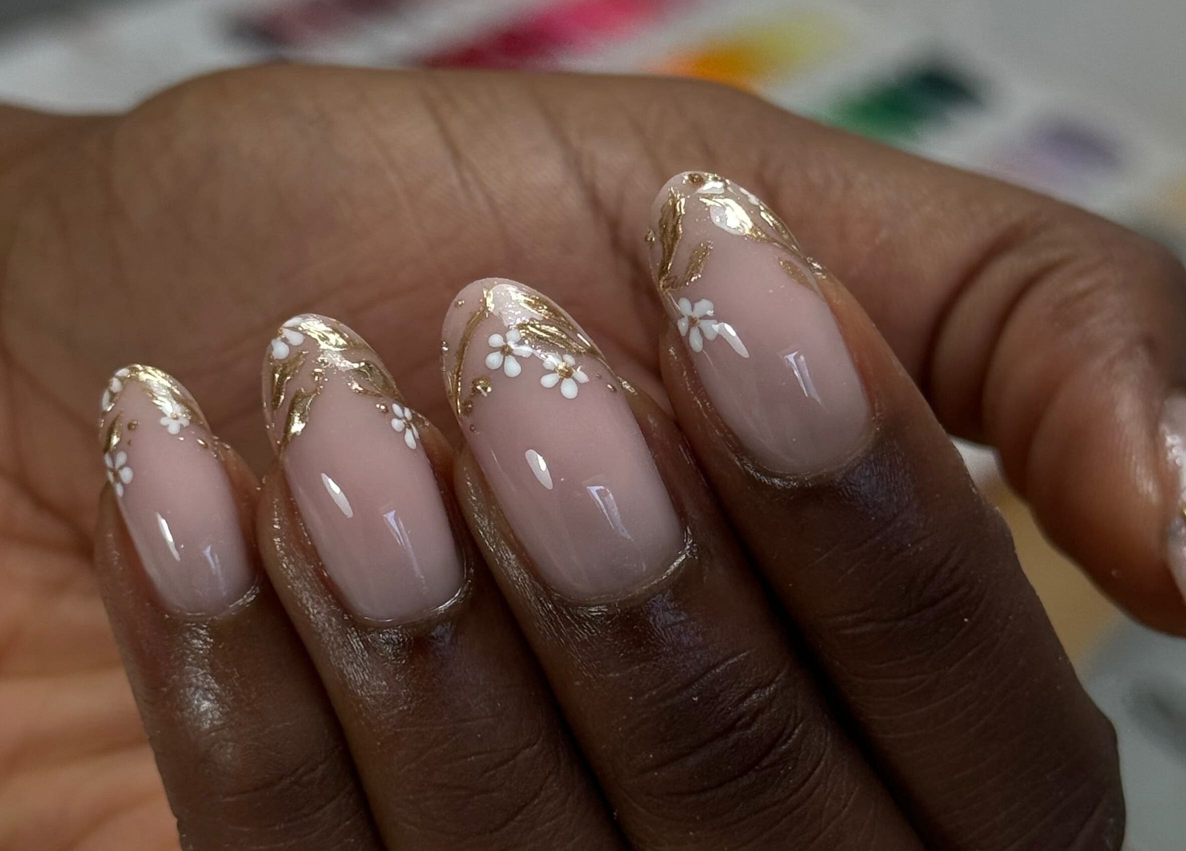Elegant floral nail art at Freshsetcait in Colchester, England, GB, featuring gold accents and delicate petals.