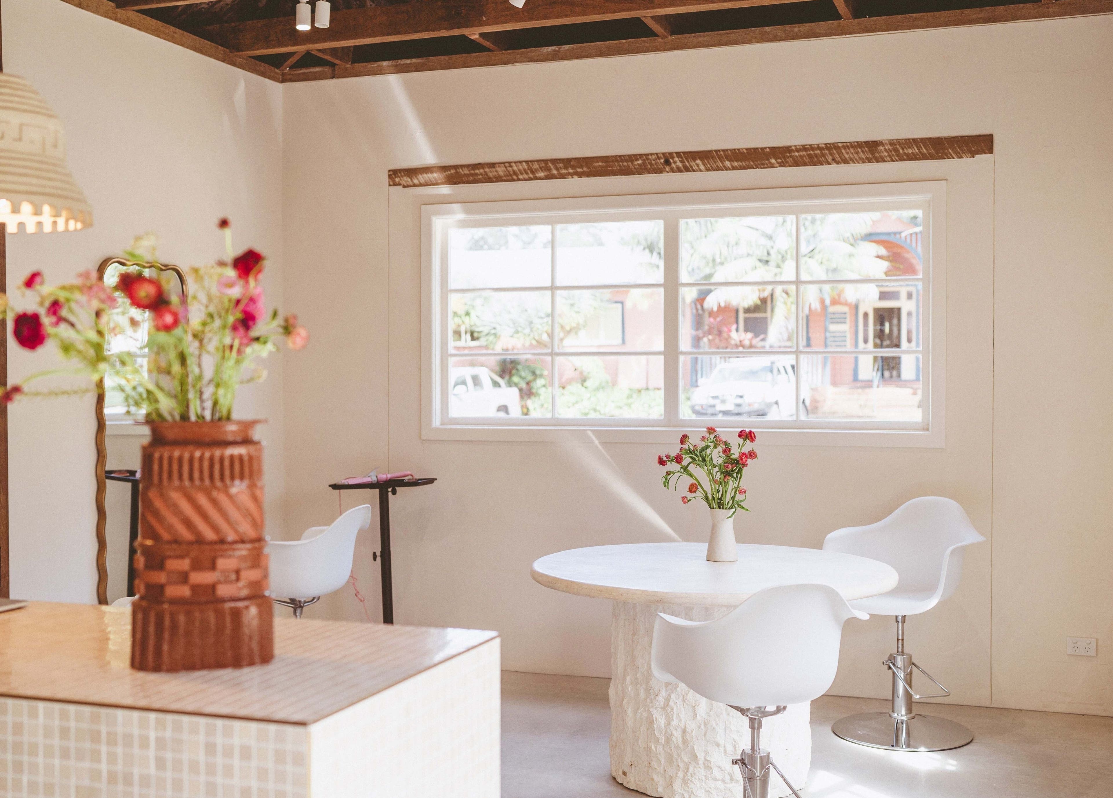Bright, modern interior of JoiE Beauty Salon in Auckland, NZ, showcasing chic decor and fresh flowers.