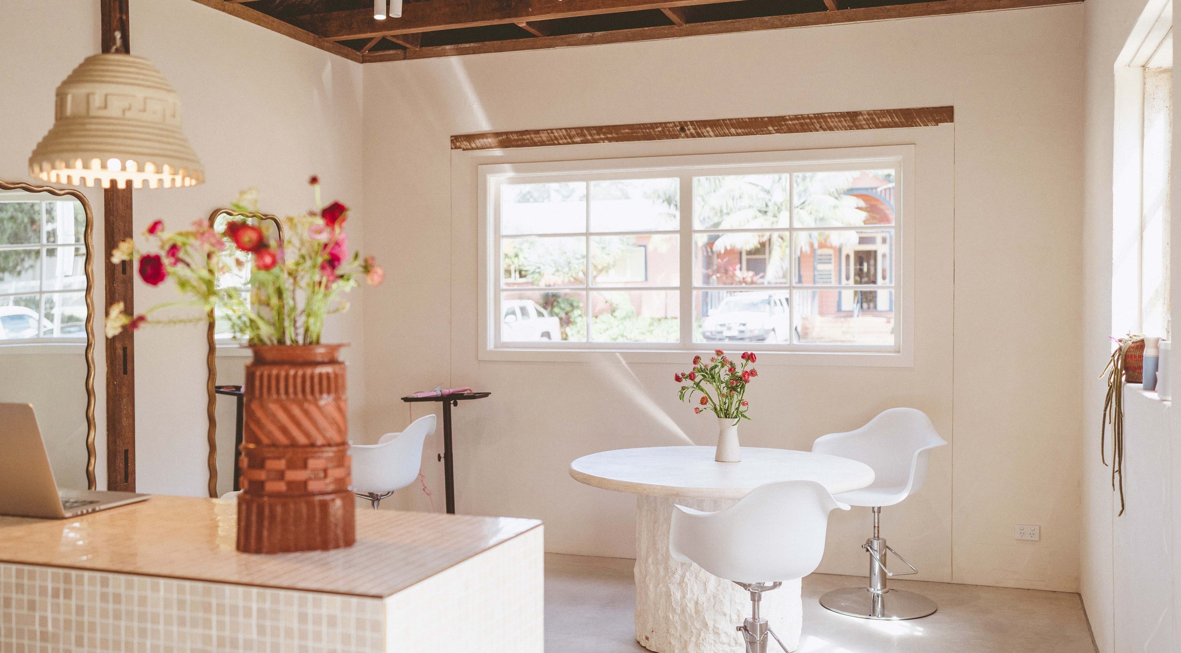 Bright, modern interior of JoiE Beauty Salon in Auckland, NZ, showcasing chic decor and fresh flowers.