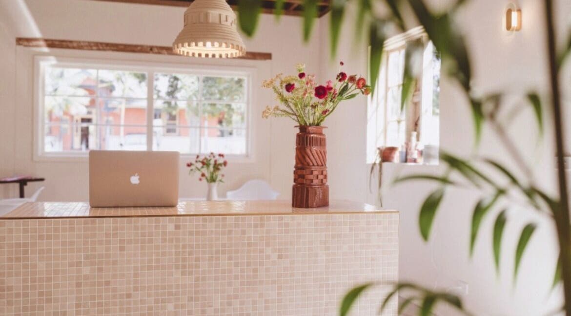 Reception desk with laptop and flowers at JoiE Beauty Salon, Auckland, Auckland, NZ.