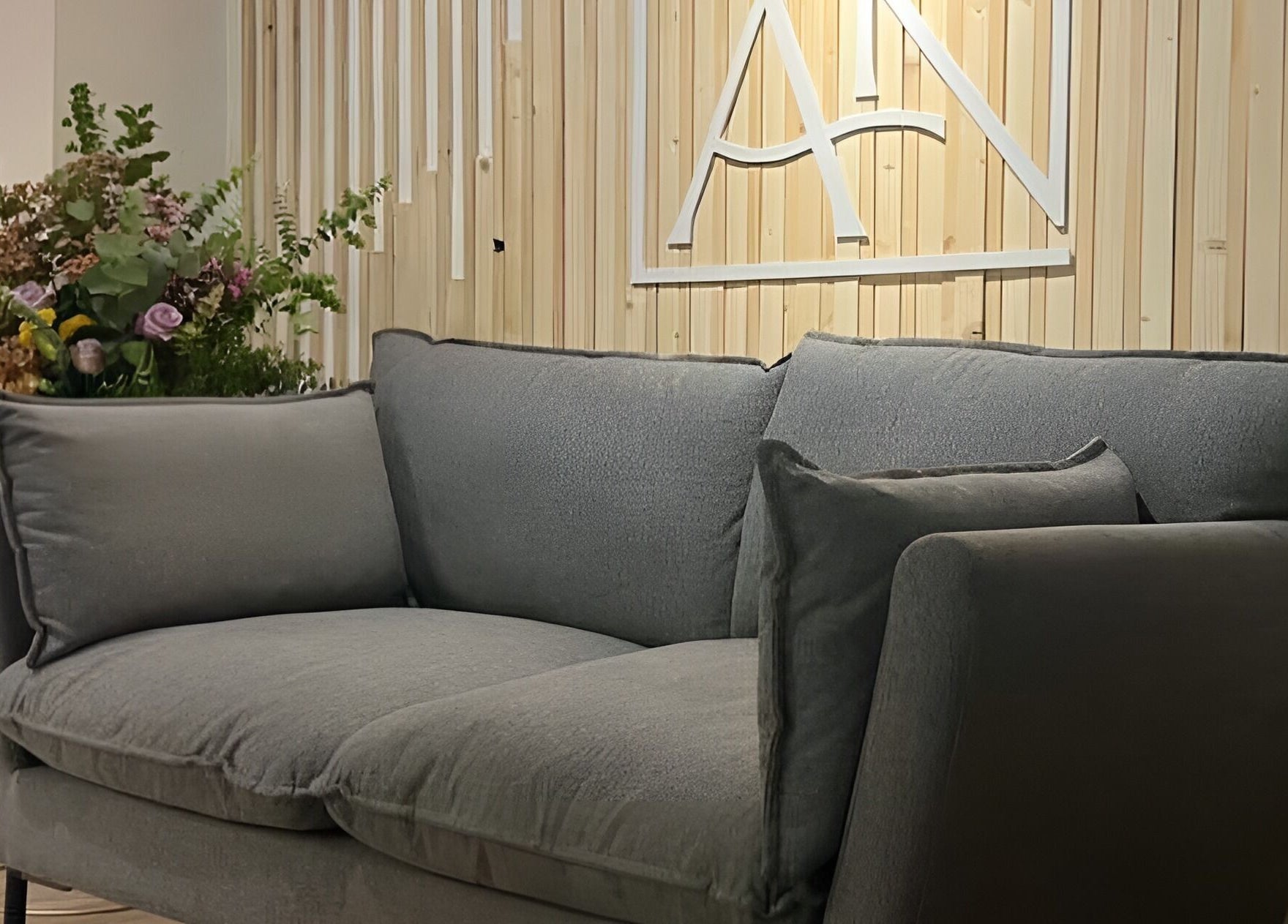 Elegante sofá en Radiance, Zaragoza, Aragón, ES con flores decorativas y fondo de madera clara.