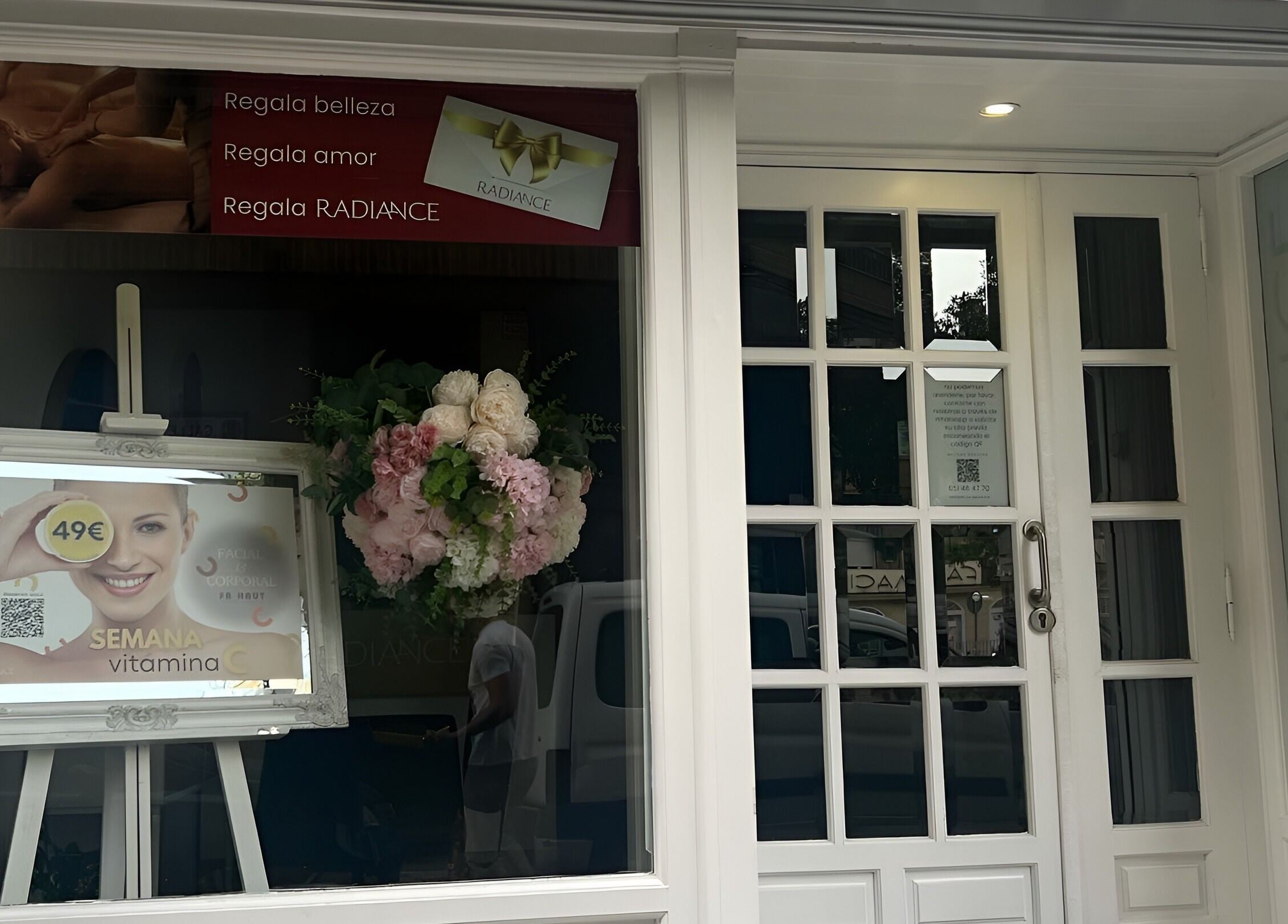 Entrada del salón de belleza Radiance en Zaragoza, Aragón, ES con cartel y flores decorativas.