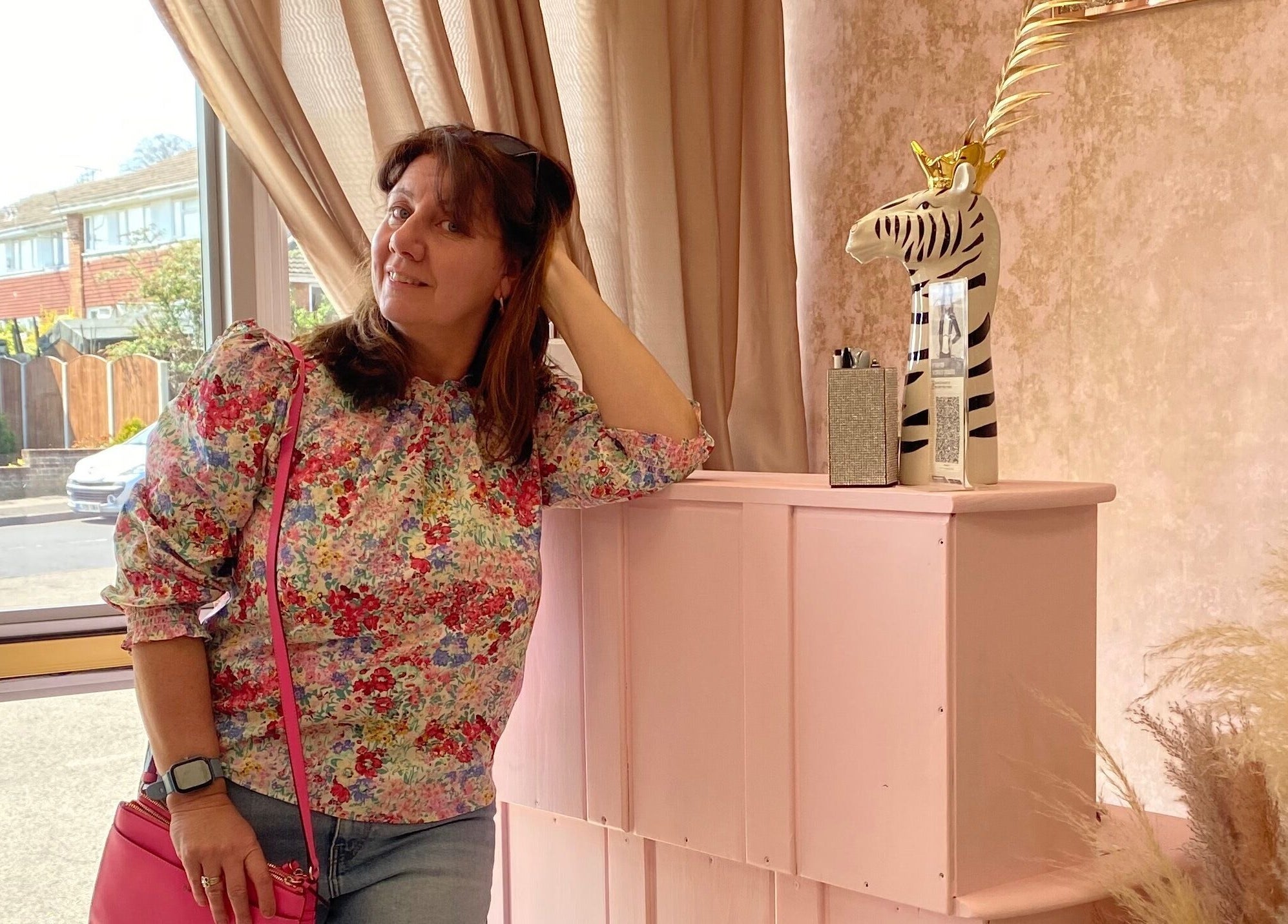 Woman in floral top at Naturally U, a beauty venue in Sittingbourne, England, GB, next to zebra decor.