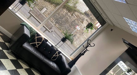 Cozy lounge area with black leather sofa at Ivy Hair & Beauty, Cowdenbeath, Scotland, GB.