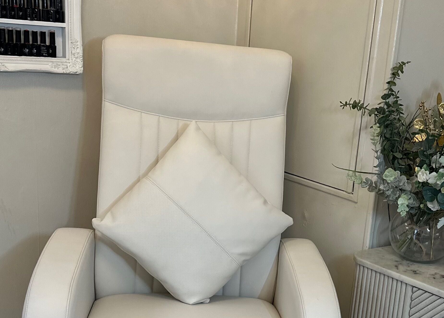 Luxurious white chair with cushion beside floral decor at The House of Beauty, Crowle, England, GB.