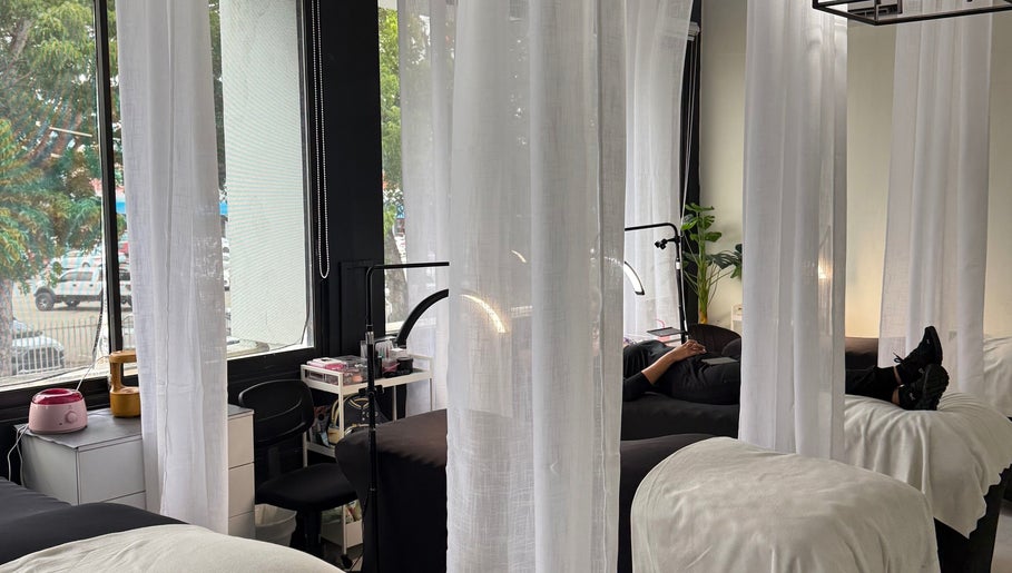 Área de relajación en Lumé Studio, Caguas, Caguas, PR con camillas y cortinas blancas.