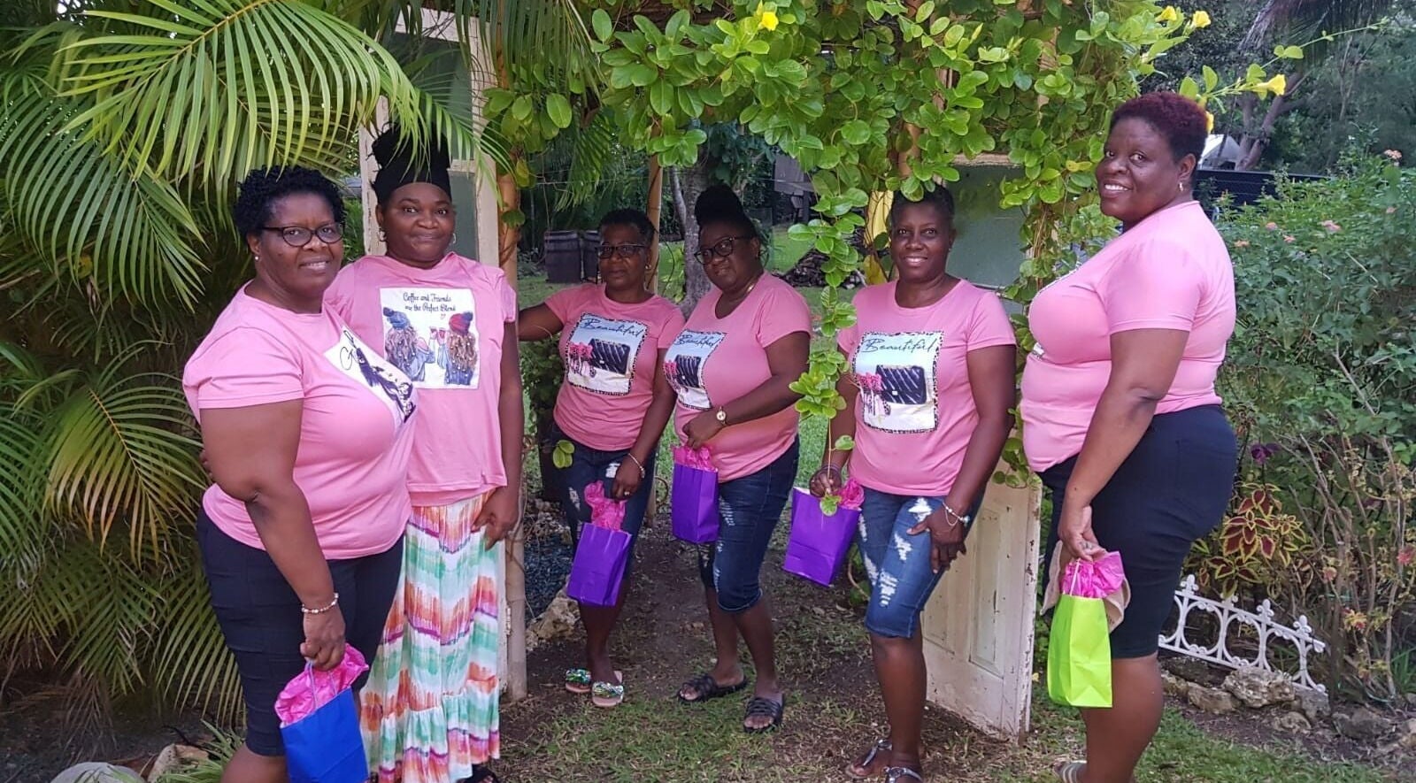 Guests smiling in pink shirts at Spa Holistic Health and Wellness, St. John, BB garden.