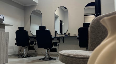 Interno del Unique Barbershop a Oristano, Sardegna, IT con sedie nere e specchi eleganti.