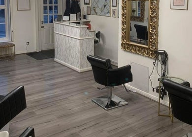 AE HAIR salon interior with sleek black chairs and golden mirrors in Grimsby, England, GB.