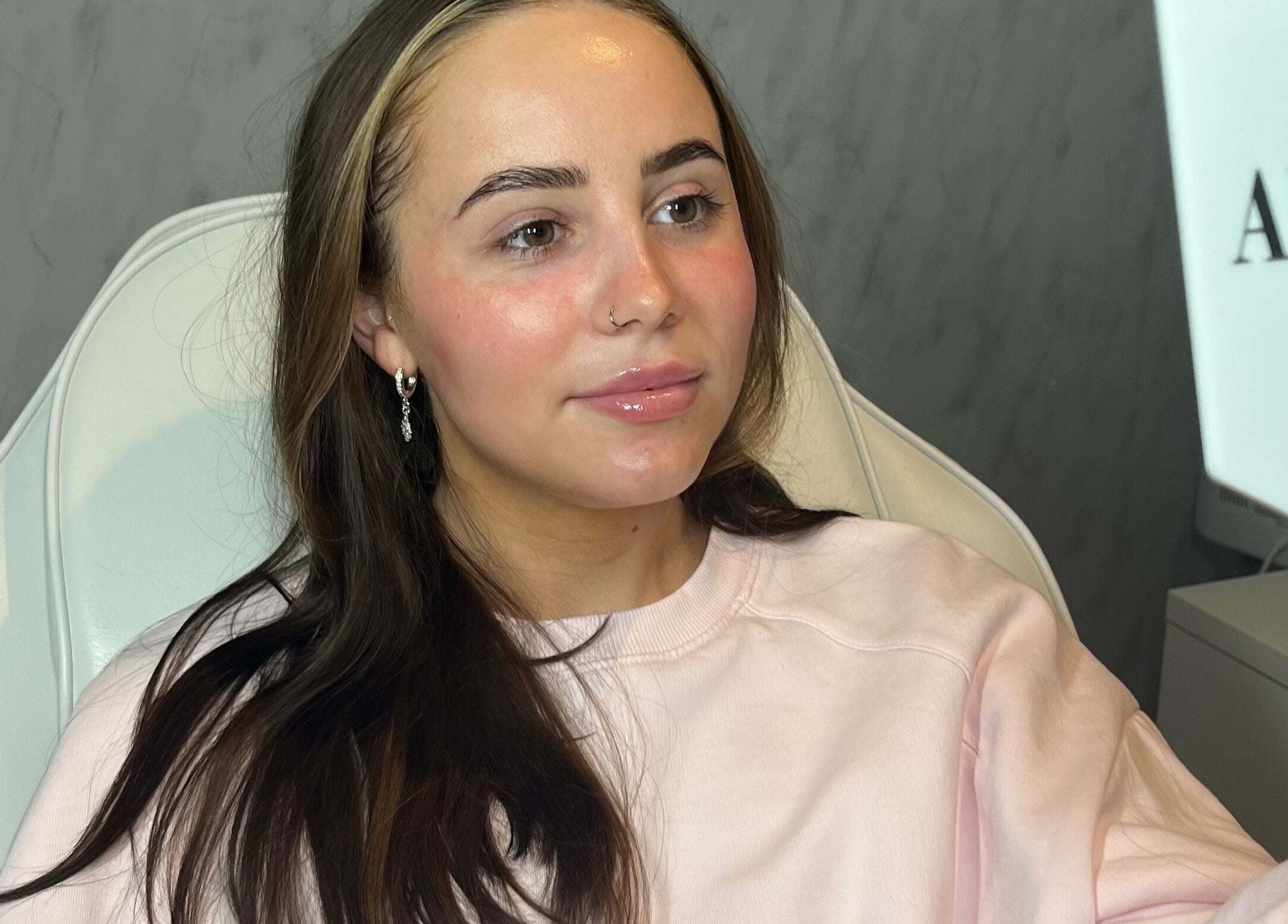 Client admiring results in mirror at TweaksByMia, Colchester, England, GB, showcasing glowing skin post-treatment.