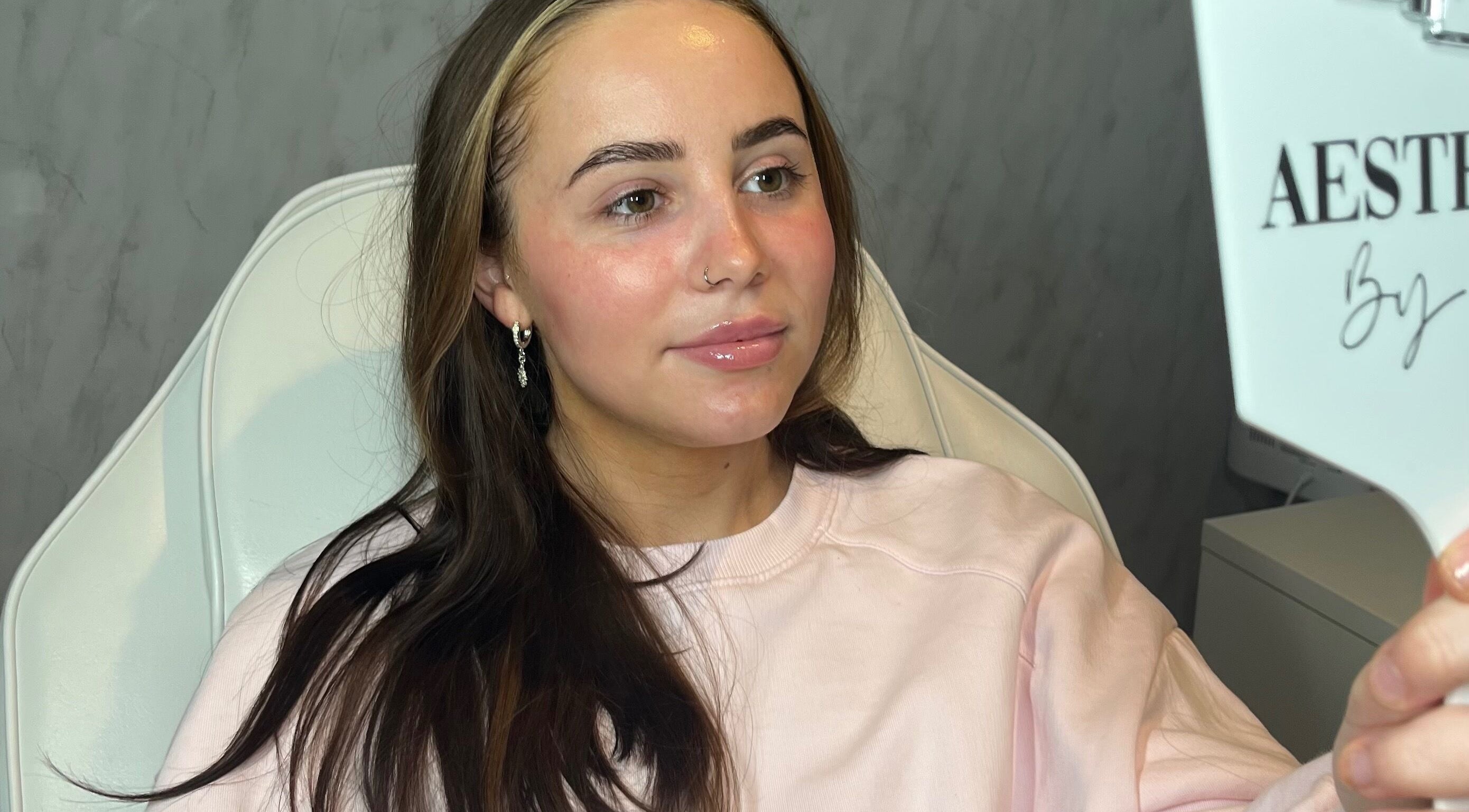 Client admiring results in mirror at TweaksByMia, Colchester, England, GB, showcasing glowing skin post-treatment.