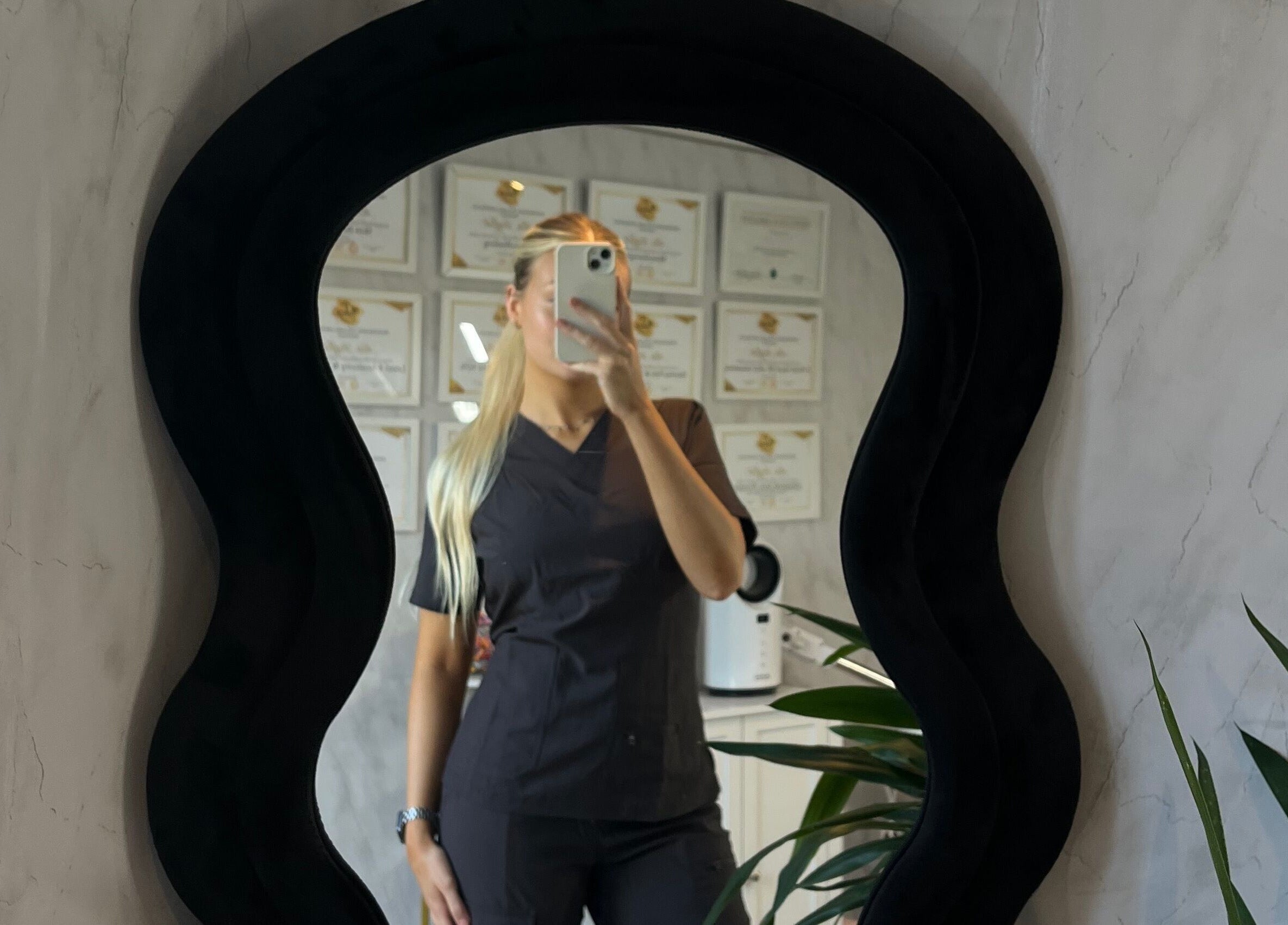 Mirror reflection of uniformed staff at TweaksByMia, Colchester, England, GB surrounded by certificates.