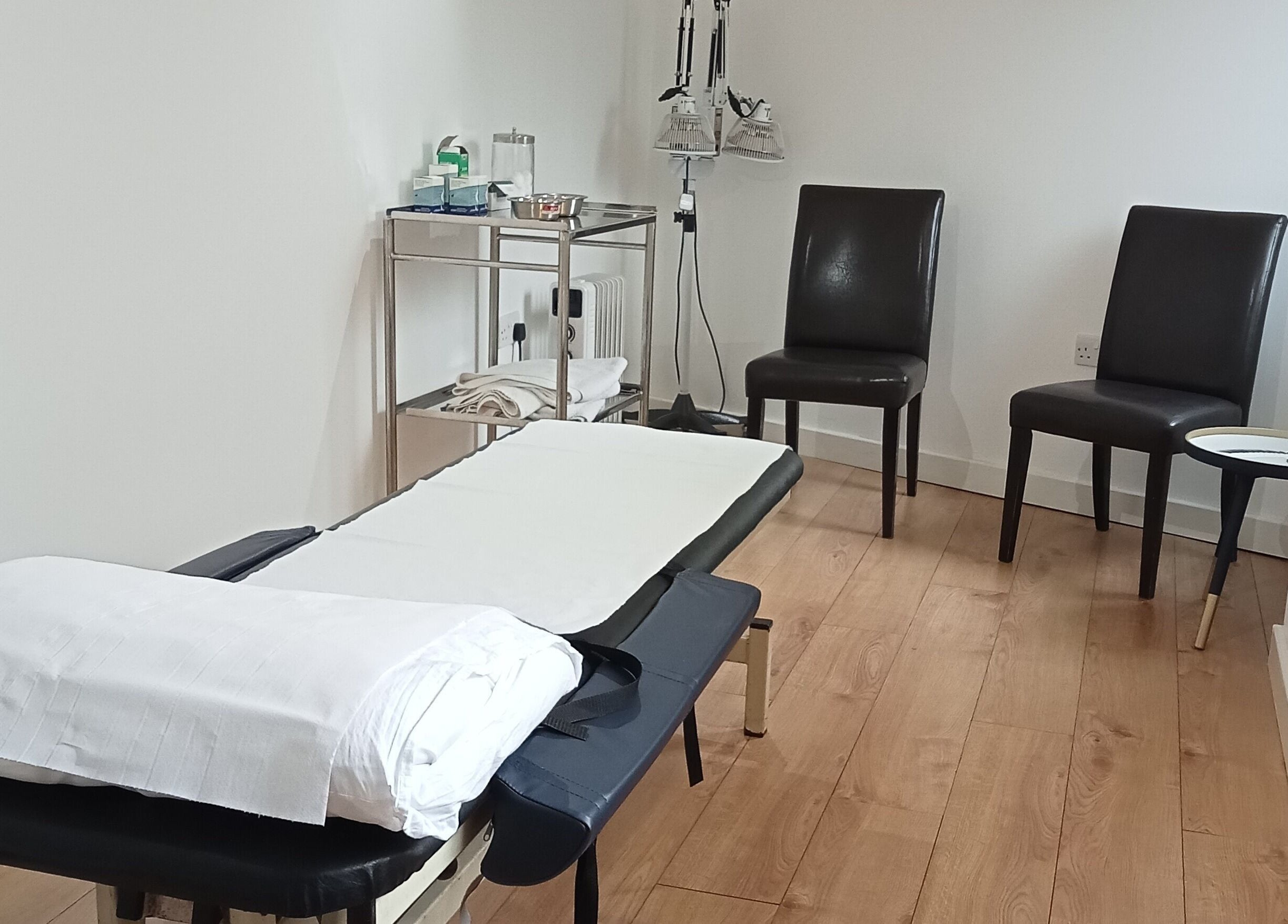 Calming therapy room at White Crane Acupuncture, Mansfield, GB, featuring a treatment table and chairs.