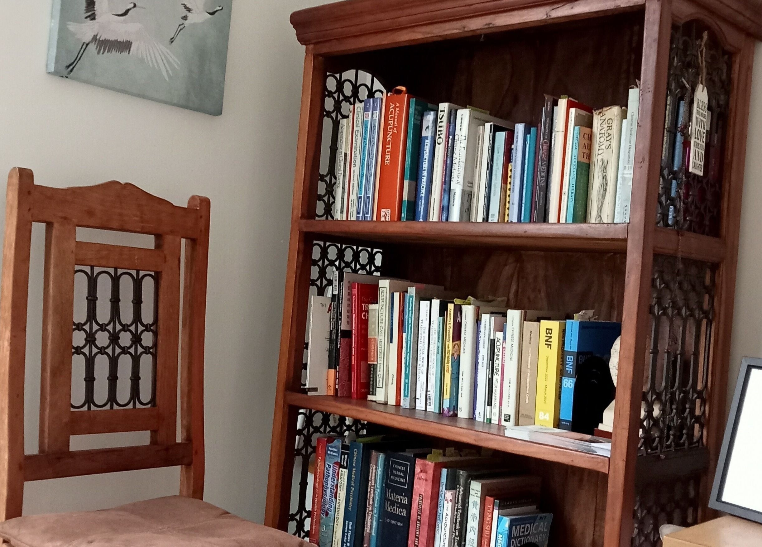 Bookshelf and chair at White Crane Acupuncture, Mansfield, GB welcoming you to a tranquil environment.