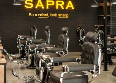 Interior moderno de SAPRA Barbershop en Miraflores, Provincia De Lima, PE, con sillas elegantes y ambiente acogedor.