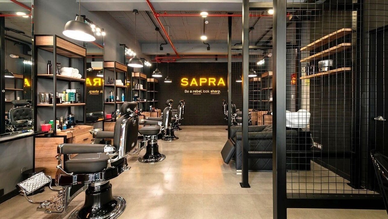 Interior moderno de Sapra Barbershop en Miraflores, Provincia De Lima, PE, mostrando sillas de barbero elegantes.